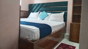 A bedroom with a bed, a wooden headboard, a white and blue bedspread, and a red rug.