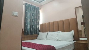A bedroom with a bed, a ceiling fan, and a window with curtains.