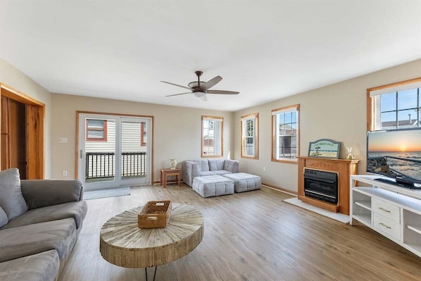 A spacious living room with a sofa, ottoman, fireplace, and a television. - 4 Bedroom Single-Family Home in North Wildwood (North Wildwood)