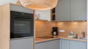 A modern kitchen with a built-in oven, a coffee maker, and a sink.