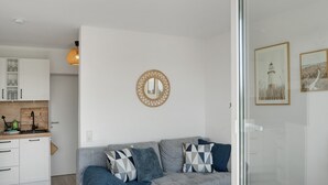 Ein modernes Wohnzimmer mit einem grauen Sofa, einem runden Spiegel und gerahmten Kunstwerken an der Wand.