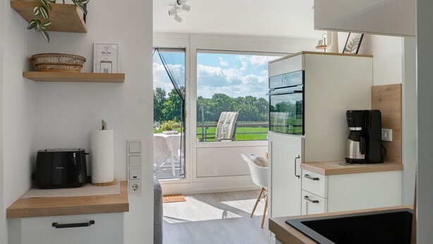 Eine moderne Küche mit Toaster, Kaffeemaschine und Blick ins Freie.