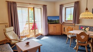 Una habitación con televisión, una mesa de comedor, sillas, un sofá y vistas al exterior.