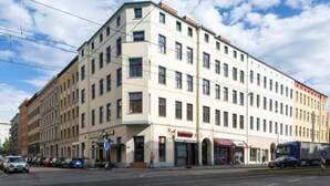 A multi-story building with a flat facade, large windows, and a corner entrance. - Central & bright | 4 persons (Magdeburg)