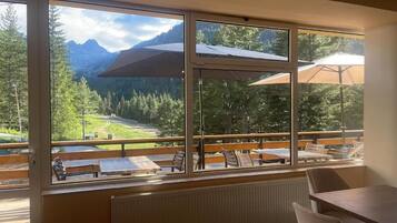 Habitación con amplios ventanales que dan a un paisaje montañoso, muebles de madera y vista a una terraza.