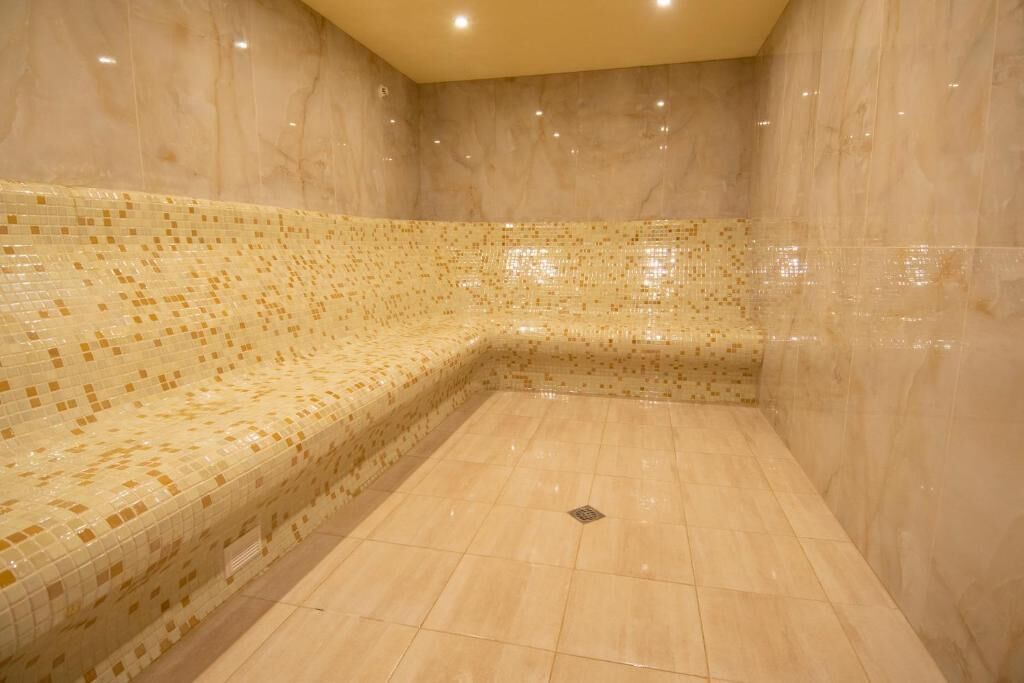 A spa room with a tiled bench and a drain in the center.