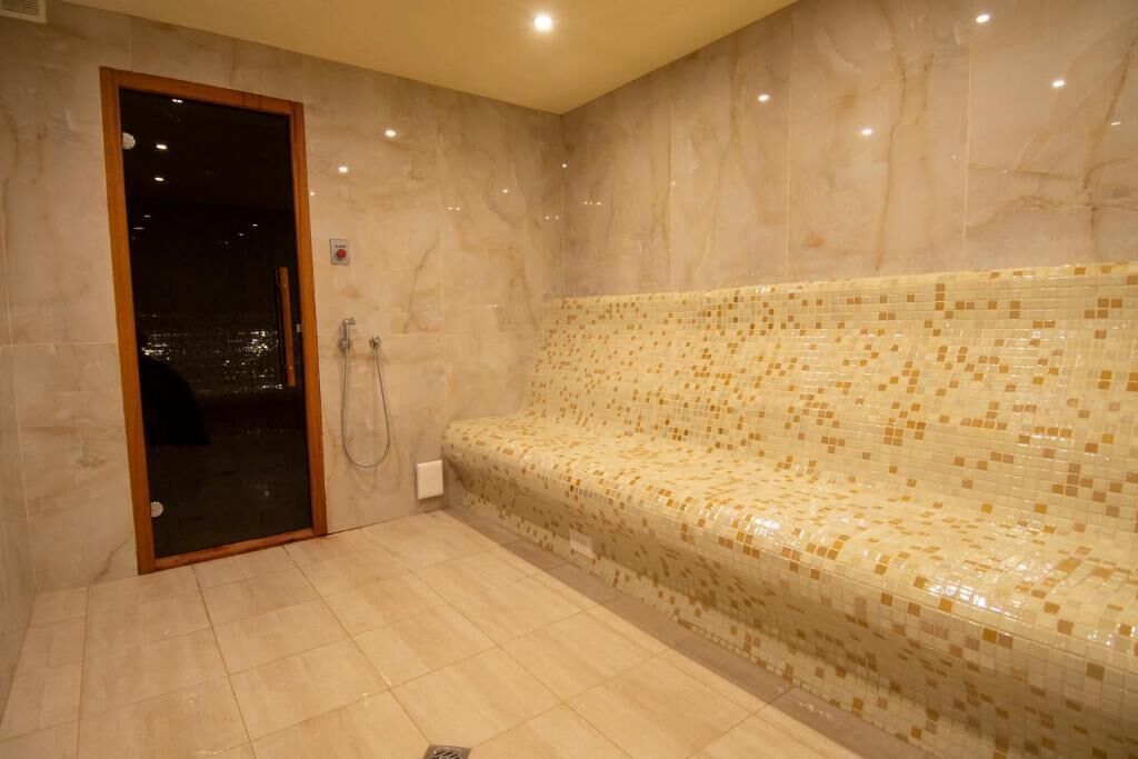 A spa room with a tiled floor, a bench, and a shower area.