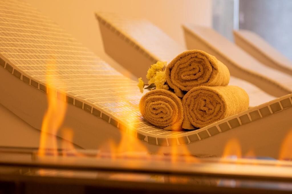 Una sauna con tre asciugamani arrotolati e un fiore su una panchina riscaldata.