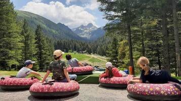 People sitting on inflatable tubes in a natural setting with mountains in the background.