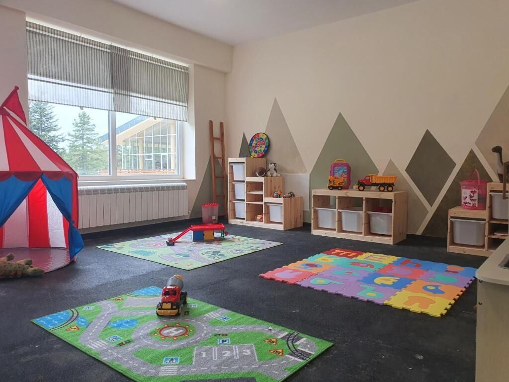 Une salle de jeux avec une grande tente, des tapis de jeu et des meubles de rangement en bois.