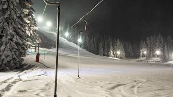 Pista de esquí nevada de noche con cables y luces de telesilla.