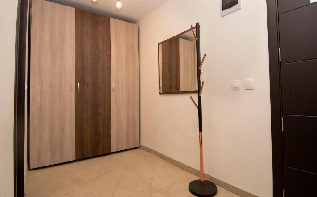 A hallway with a wooden wardrobe, a mirror, and a coat stand.