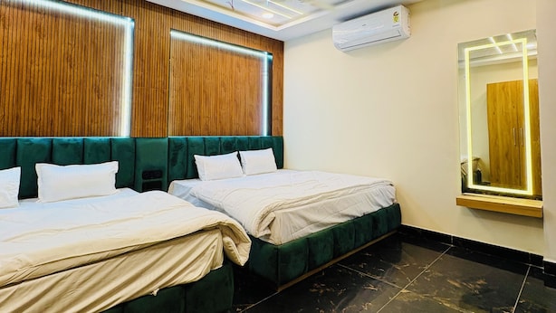 A hotel room with two beds, a wooden headboard, a large mirror, and a ceiling fan. - Hotel Naagshree (Ujjain)