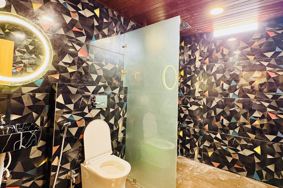 Un baño moderno con un reverso de azulejos geométricos, techo de madera y separador de vidrio.