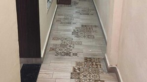 A hallway with patterned floor tiles, a water dispenser, and a door at the end. - Hotel Naagshree (Ujjain)