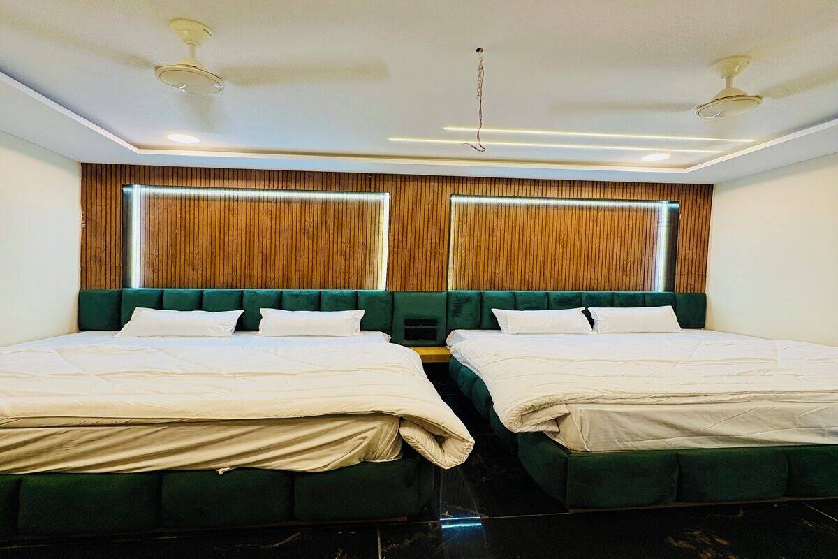 Habitación de hotel con dos camas, cabecera de madera y diseño moderno en el techo.