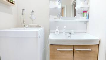 A bathroom with a white washing machine, a sink with a mirror above it, and wooden cabinets.