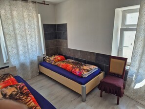 A bedroom with a bed, a chair, a window, and a door.