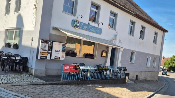 A two-story building with a sign reading 'Zur Sonne' and a visible storefront. - Apartment 'Appartement Aurach A6' with Wi-Fi (Aurach)