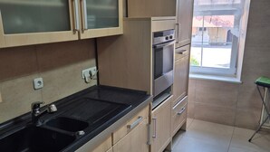 A kitchen with a double sink, wooden cabinets, a built-in oven, and a window with a view. - Apartment 'Appartement Aurach A6' with Wi-Fi (Aurach)