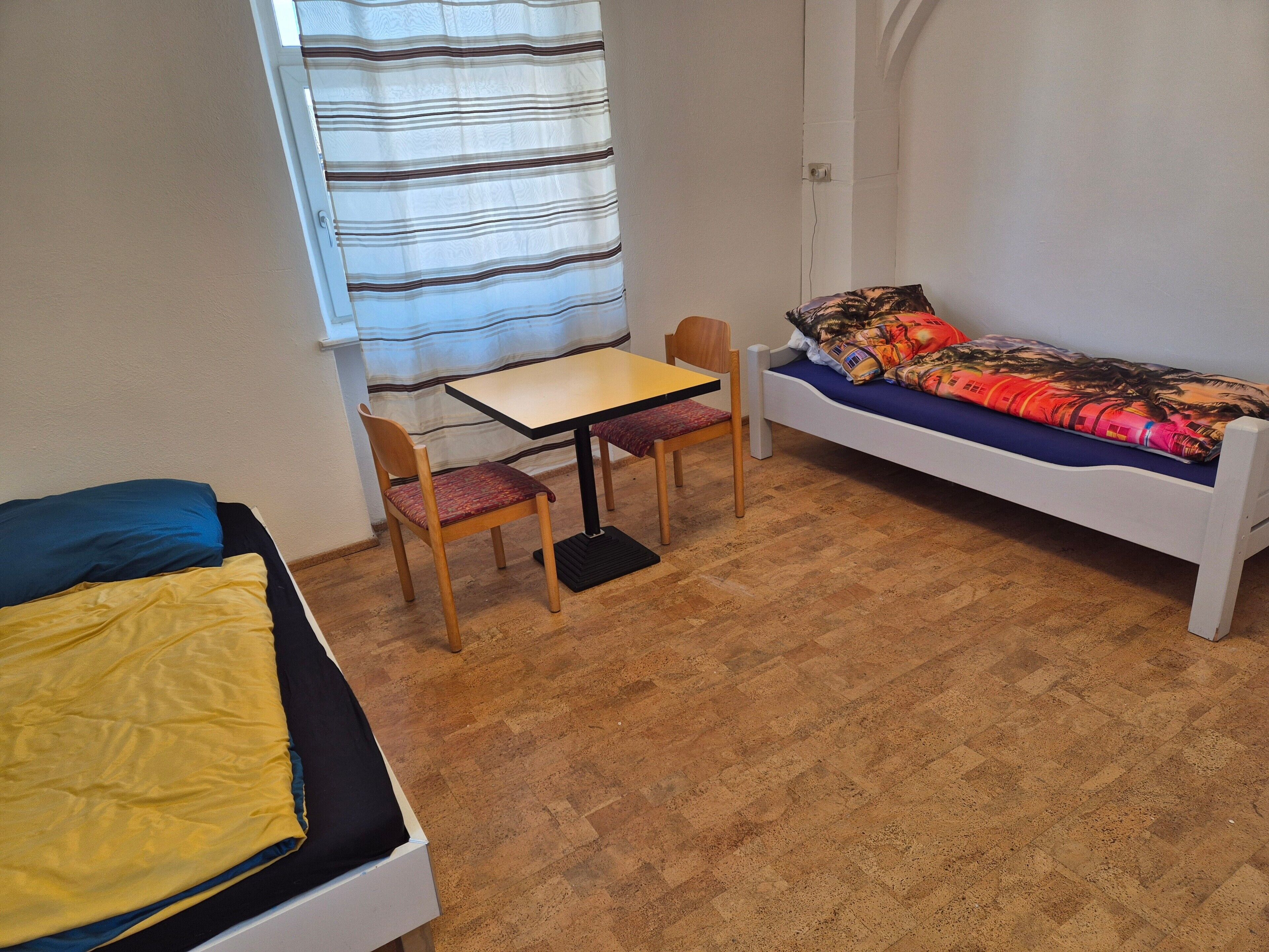 A small room with a bed, a table, two chairs, and a sofa.