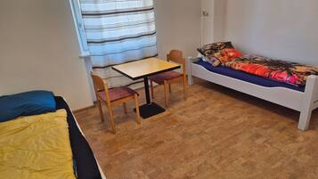 A small room with a bed, a table, two chairs, and a sofa.
