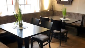 A restaurant interior with a dining area featuring tables and chairs, a bench, and a wall-mounted mirror.