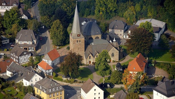An aerial view of a town with a prominent church, residential buildings, and a mix of modern and traditional architecture.