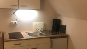 A compact kitchen with a built-in stove, a sink, and a coffee maker.