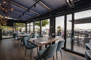 Enjoy meals in a comfortable dining area with wooden tables and chairs, offering views of the surrounding area.