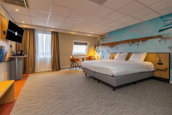Relax in comfort with a large bed, desk, and wall-mounted TV.
