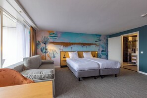 Relax in this stylish room featuring a large bed, sofa, and wall mural.
