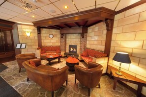 Relax by the fireplace in this inviting lounge area, featuring comfortable seating and a warm ambiance.