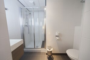 Bathroom features a glass-enclosed shower with handheld showerhead and wall-mounted faucet, a toilet, and a tiled floor.