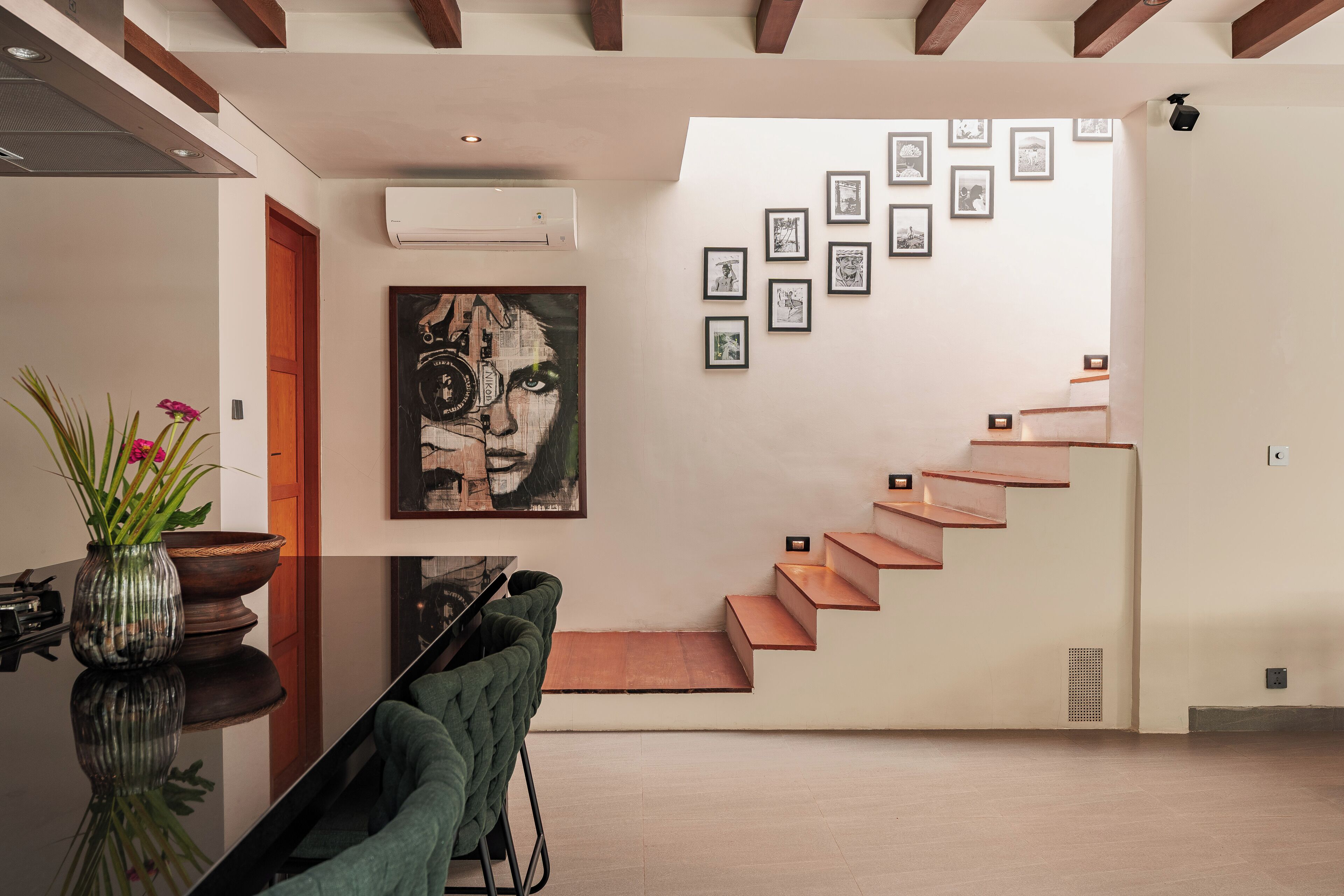 A modern interior with a staircase, artwork, and a dining area.