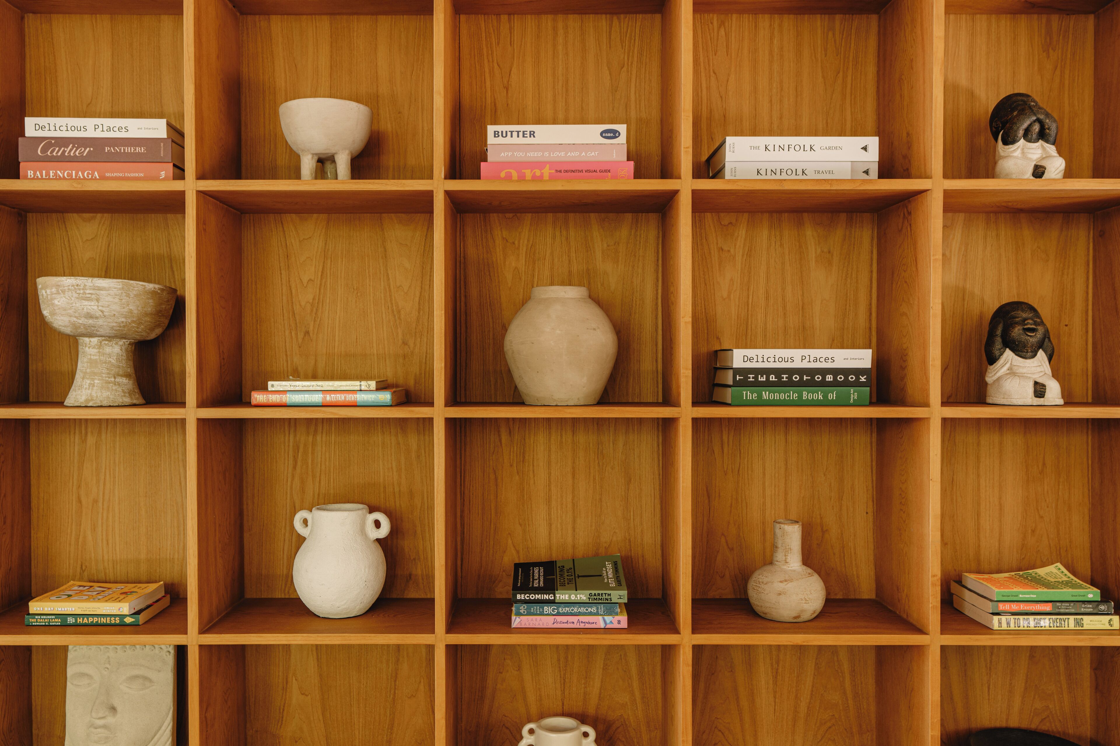 A wooden bookshelf with various books and ceramic items.