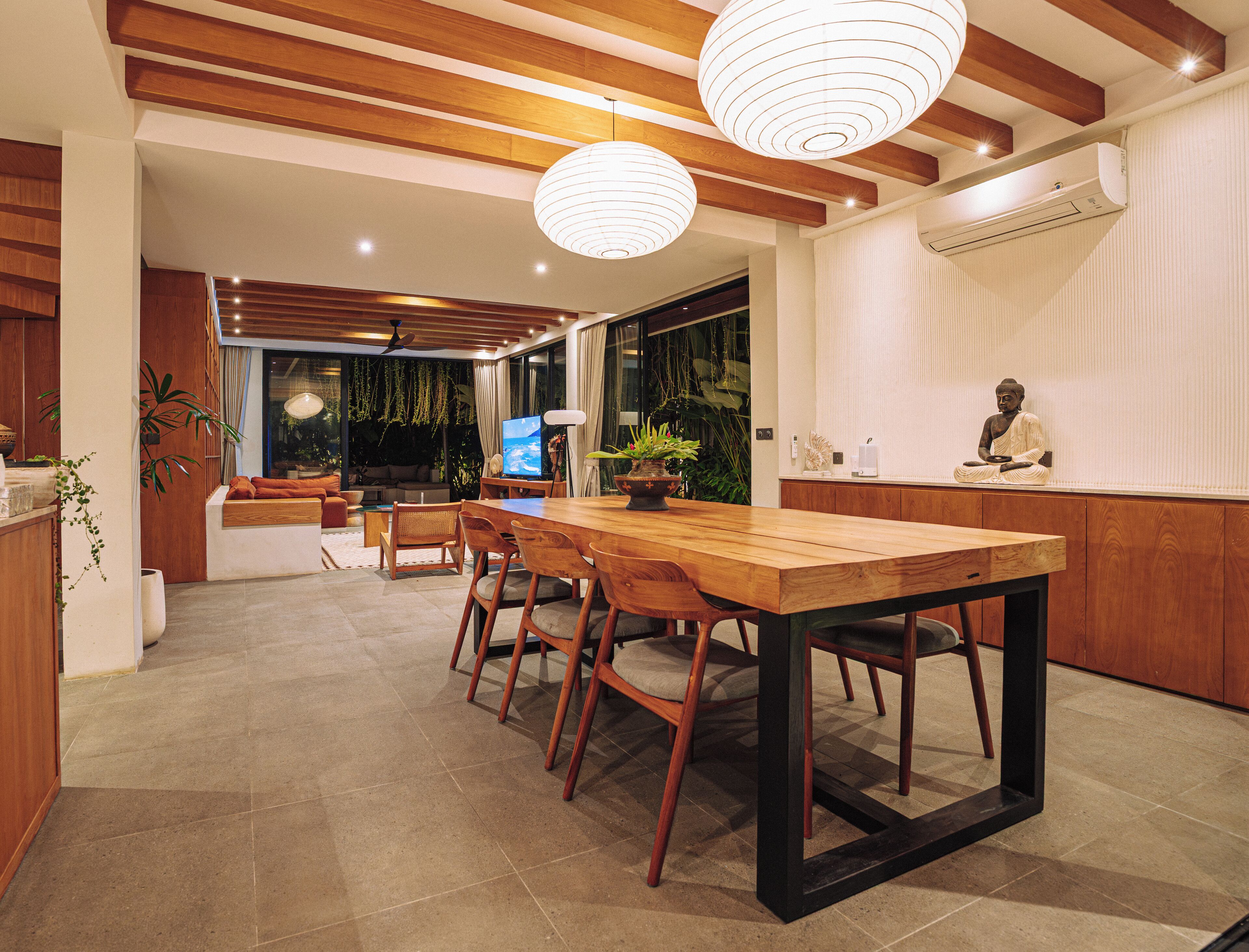 Una cocina moderna con una mesa de comedor de madera, sillas y lámparas colgantes.