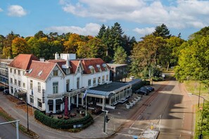 Stunning building with a red-tiled roof, featuring a grand entrance and outdoor seating area.