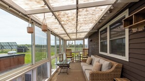 A covered porch with a sofa, chairs, and a table.
