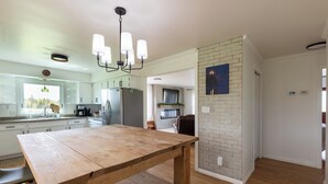 A spacious kitchen with a wooden table, modern appliances, and a brick accent wall.