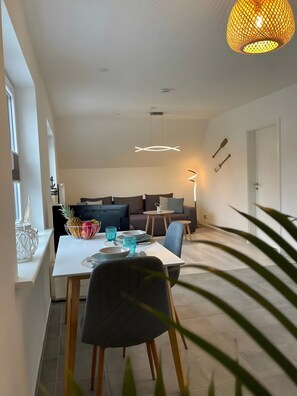 A modern kitchen with a dining area, a large window, and a hanging light fixture. - Apartment 'Nordstrand' with Balcony and Wi-Fi (Nordstrand)