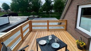 Una terraza con una mesa, sillas, un ventanal y vistas del entorno.