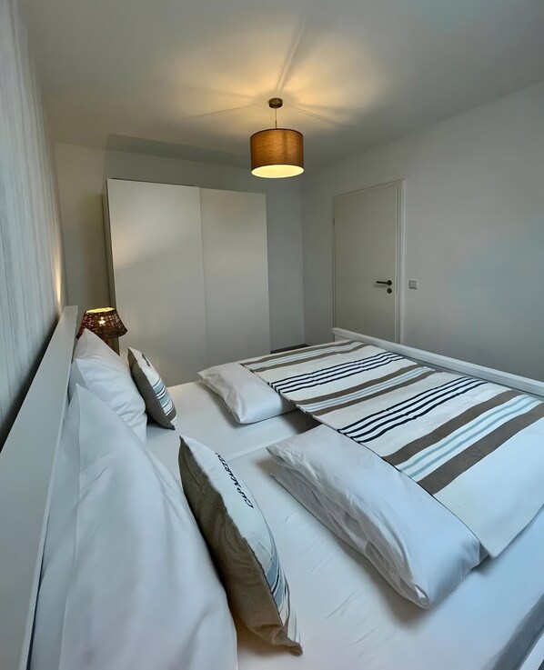 Una habitación de hotel con dos camas, un ventilador de techo y una puerta.