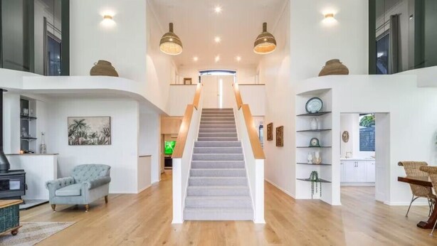 A spacious living area with a central staircase, wooden flooring, and a modern design. - 6 Bedroom Oasis in Burleigh Heads (Burleigh Heads)