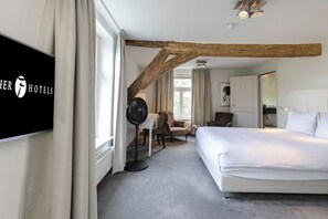 Relax in a serene space with a large bed, desk, and flat-screen TV.