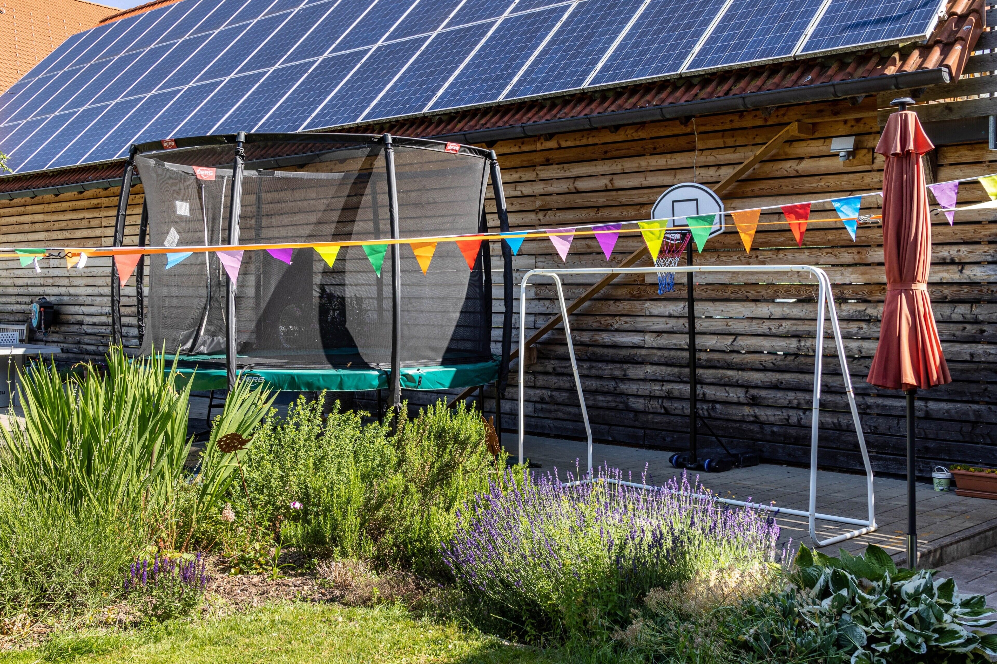 Una cabaña de madera con un trampolín, un aro de baloncesto y un conjunto de paneles solares.