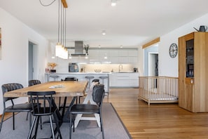 Une cuisine moderne avec des meubles blancs, une table à manger en bois et des chaises noires.