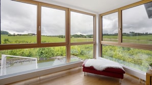 Una habitación con ventanas amplias, suelo de madera y un banco rojo.