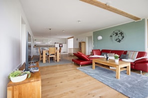 Un salon moderne avec un canapé rouge, une table basse en bois et un tapis gris.