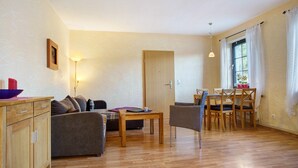 Una sala de estar con sofá, una mesa de madera y un comedor con sillas.